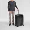 Person holding a black Victorinox suitcase on a light gray background