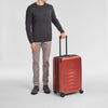 Person holding a red Victorinox suitcase on a light gray background