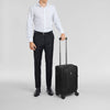 Man in formal attire holding a black Victorinox suitcase on a light gray background