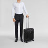 Man in formal attire holding a black Victorinox suitcase on a light gray background