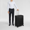 Man in formal attire holding a black Victorinox suitcase on a light gray background