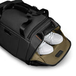 Black Briggs & Riley duffel bag with white sneakers inside on a white background