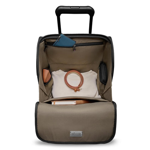 Open Briggs & Riley suitcase with clothes and accessories on a white background