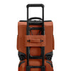 Orange Briggs & Riley  suitcase with black handle and wheels on a white background
