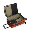Open orange Briggs & Riley suitcase with black interior on a white background