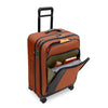 Orange Briggs & Riley suitcase with front pockets packed on white background