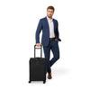 Model with black Briggs & Riley Baseline Essential Carry-On Spinner