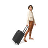 Model with black Briggs & Riley Baseline Global 2-Wheel Carry-On