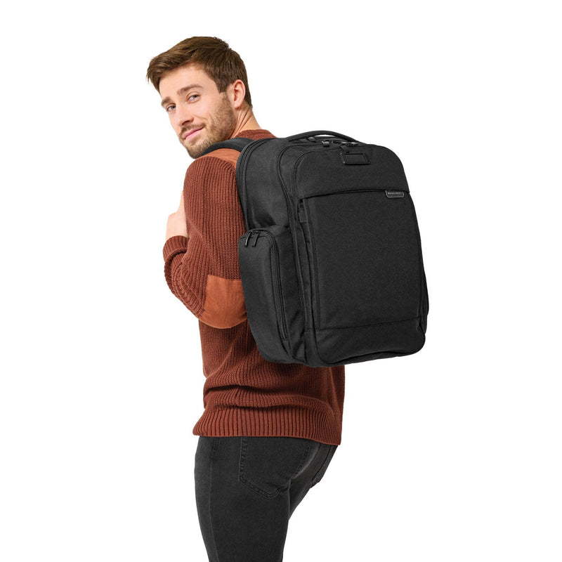 Model with black Briggs & Riley Baseline Traveler Backpack