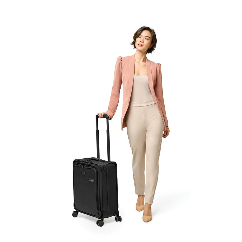 Model with black Briggs & Riley Baseline Global Carry-On Spinner