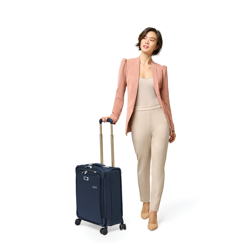 Model with navy Briggs & Riley Baseline Global Carry-On Spinner